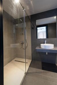 巴统BET25 Hotel的一间带玻璃淋浴和水槽的浴室