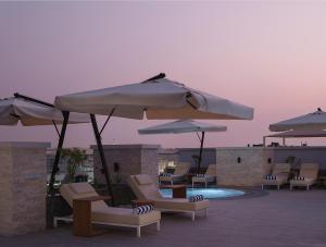 马斯喀特DoubleTree by Hilton Muscat Qurum的一组椅子和遮阳伞,位于游泳池旁