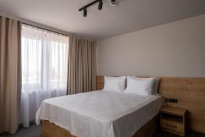 巴统BET25 Hotel的一间卧室配有一张带白色床单的床和一扇窗户。