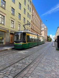 赫尔辛基Design stay in the heart of Punavuori的一条绿色和黄色的电车在城市街道上