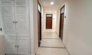 海得拉巴FabHotel Prime AM Suites Near Yashoda Hospital的走廊设有白色门,铺有瓷砖地板。