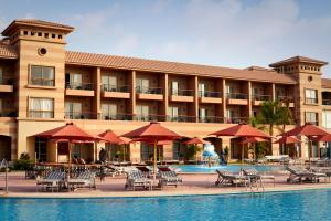 艾因苏赫纳Coral Sea Beach and Aqua Park的酒店设有一个游泳池、桌子和遮阳伞