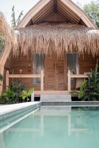 吉利阿尔My Island Home Gili Air的一座带茅草建筑和游泳池的度假村