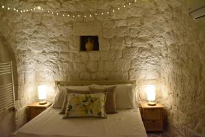 奥斯图尼Terre d'amore - For couples的一间卧室设有石墙、一张床和两盏灯。