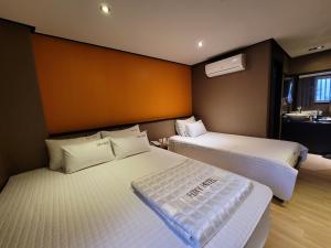 釜山Foxy Hotel的一间带两张床的卧室和一间带水槽的浴室