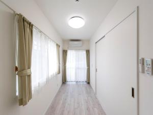 名户Hotel Tomas Nago的走廊设有白色的墙壁和窗户