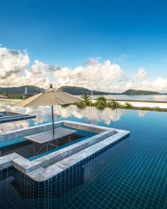芭东海滩Andamantra Resort and Villa Phuket - SHA Extra Plus的一个带遮阳伞和水的游泳池
