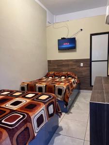 查察拉卡斯Hotel MARU Pool & Events的墙上配有电视的房间里设有三张床