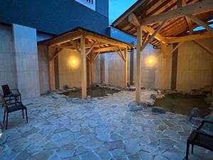 秩父市Hotel Route Inn Grand Chichibu的石头庭院,在一座建筑中设有木制凉亭