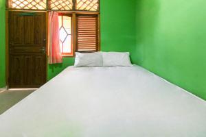 Labu SumbawaOYO 92908 Hotel Jayanni的绿色客房内的一张大床,设有窗户