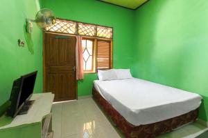 Labu SumbawaOYO 92908 Hotel Jayanni的绿色的客房配有床和电视
