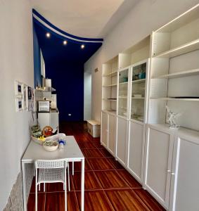 焦维纳佐Casadamare Holiday Home的厨房配有白色橱柜和桌椅