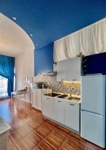 焦维纳佐Casadamare Holiday Home的厨房配有白色橱柜和蓝色的墙壁