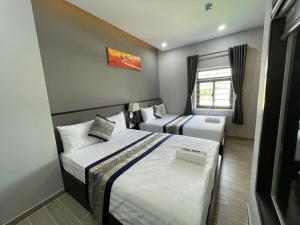 Bến CátAnna Hotel Binh Duong的一间卧室设有两张床和窗户。