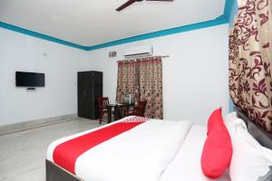BāliantaOYO Maa Banadurga Guest House的一间卧室配有一张床和一张桌子及一台电视