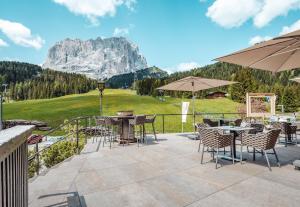 塞尔瓦迪加尔代纳山谷Hotel Plan De Gralba - Feel the Dolomites的一个带桌椅的庭院和山脉