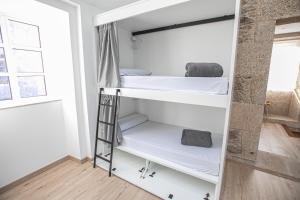 圣地亚哥－德孔波斯特拉Albergue A Fabrica的客房设有两张双层床和梯子