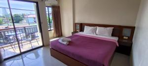 芭东海滩KANPAI HOTEL的一间卧室配有一张带紫色毯子的床和一个阳台
