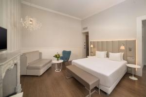 热那亚热那亚中心NH酒店的卧室配有一张白色的大床和一张沙发。
