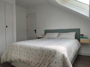 拉科萨Ático con vistas en Raxó的卧室配有一张带白色棉被的床和窗户。