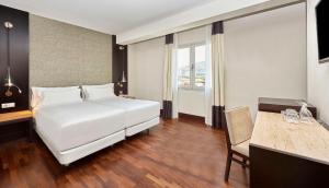 巴塞罗那NH巴塞罗那体育场酒店的一间酒店客房,配有一张白色的床和一张书桌
