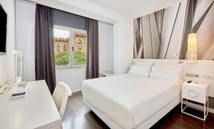 巴塞罗那NH巴塞罗那体育场酒店的白色的卧室设有床、书桌和窗户