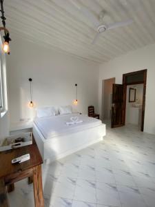 南威Cactus lodge Zanzibar的卧室配有白色的床和木桌