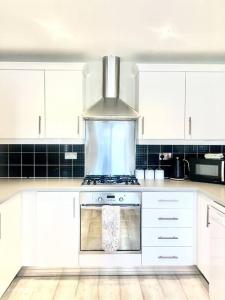 切斯特菲尔德Modern 3 bed home, Chesterfield的厨房配有白色橱柜和炉灶烤箱。