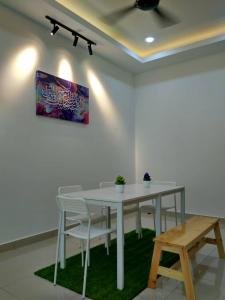 峇株巴辖HOMESTAY BATU PAHATKU- HOMESTAY IMAN的一张带椅子的白色桌子和墙上的一幅画