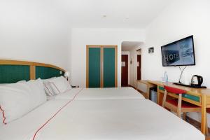 卡武埃鲁Hotel Carvoeiro Plaza的酒店客房配有两张床和一张书桌