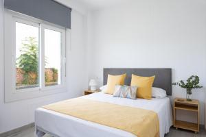 马拉加Apartamentos LA PELUSA的白色卧室配有一张带黄色枕头的大床