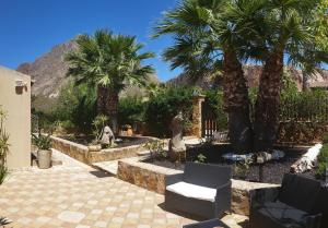 库斯托纳奇Holiday Home Baia Cofano的一个带棕榈树、椅子和围栏的花园