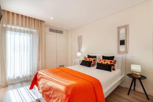 布拉加Apartamento Lírio - Minho's Guest的白色卧室配有带橙色毯子的床