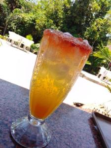 卢萨卡Palm Kalash Hotel的坐在桌子上的玻璃杯里喝一杯