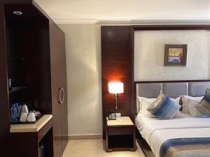 卢萨卡Grand Palace Hotel Lusaka的酒店客房配有一张床和一张带台灯的桌子