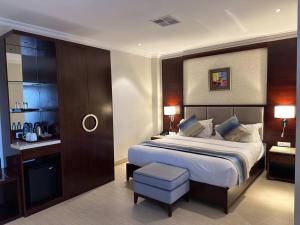 卢萨卡Grand Palace Hotel Lusaka的一间卧室配有一张大床和一张凳子