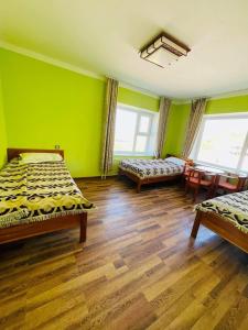 DzuunmodSara's Camp的绿色的客房设有两张床和一张桌子及椅子