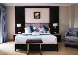 卢萨卡Grand Palace Hotel Lusaka的一间卧室配有一张大床和一把椅子