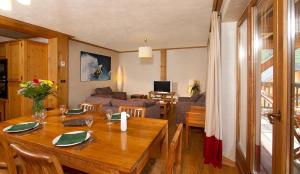 莱德萨阿尔卑斯Vacancéole - Résidence Cortina的用餐室和带木桌的客厅