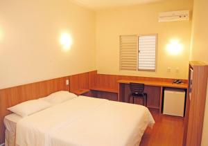 ItuiutabaBernal Hotel Econômico的一间卧室配有一张床、一张书桌和一个窗户。