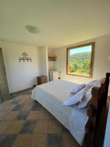 拉夫拉斯诺瓦斯Chales Sitio dos Ventos的一间卧室设有一张大床和一个窗户。