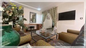 阿尤恩Hotel Al Massira的客厅配有桌子和电视
