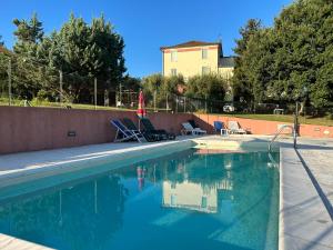 Montalto delle MarcheLa Filanda的房屋旁的游泳池配有椅子和遮阳伞