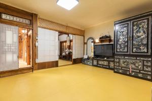 首尔Dongmyo Hanok Sihwadang - Private Korean Style House in the City Center with a Beautiful Garden的客房铺有黄色地板,配有电视。