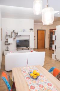 罗马Cozy flat with terrace at Trastevere train station的客厅配有白色沙发,桌子上放着一碗水果