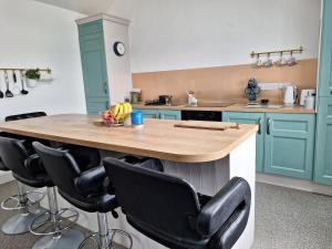贝尔马利特Teach Aindí (newly renovated cottage)的厨房配有蓝色橱柜和带黑色椅子的岛屿