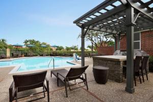 艾迪生胡伍德达拉斯 - 艾迪生酒店的一个带烧烤架和桌椅的庭院,毗邻一个游泳池