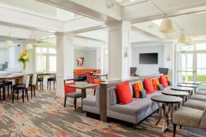 欧文达拉斯-欧文拉斯科琳娜希尔顿惠庭套房酒店的大房间设有桌子和椅子,提供橙色枕头