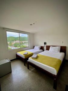 布卡拉曼加HOTEL RIVERA CENTRAL的带大窗户的客房内的两张床
