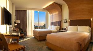 达拉斯Canopy By Hilton Dallas Uptown的酒店客房带两张床、书桌以及一间客房。